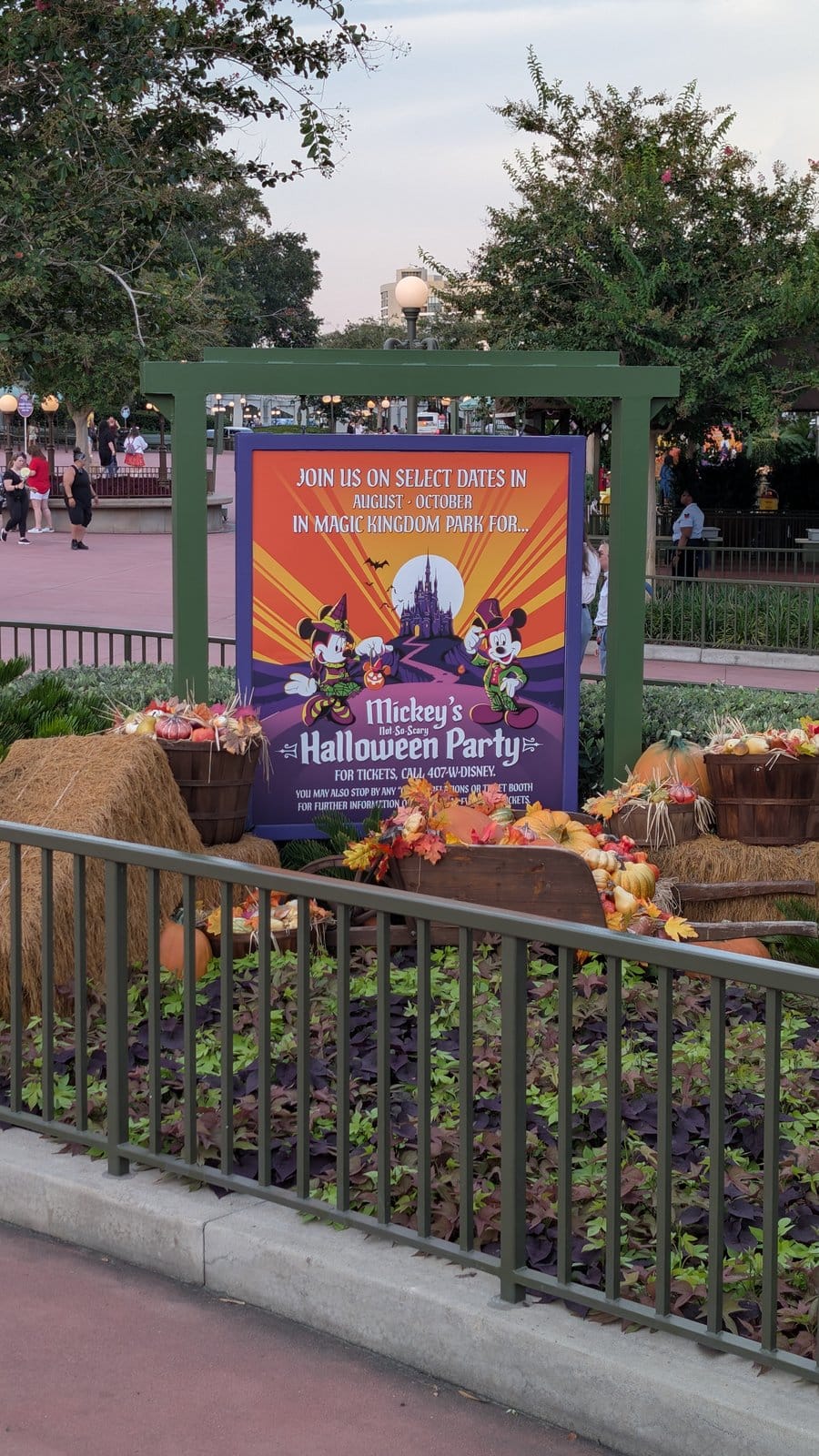 A Mickey's Not-So-Scary Halloween Party sign among fall decor at the Magic Kingdom entrance