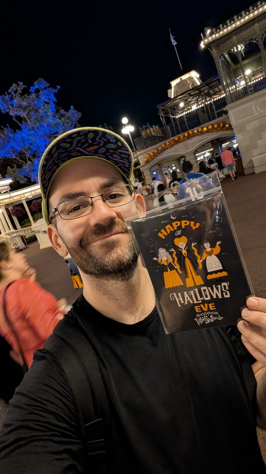 Philip Hernandez holding the Hocus Pocus Villain Spelltacular postcard from the party's glow-in-the-dark postcard set