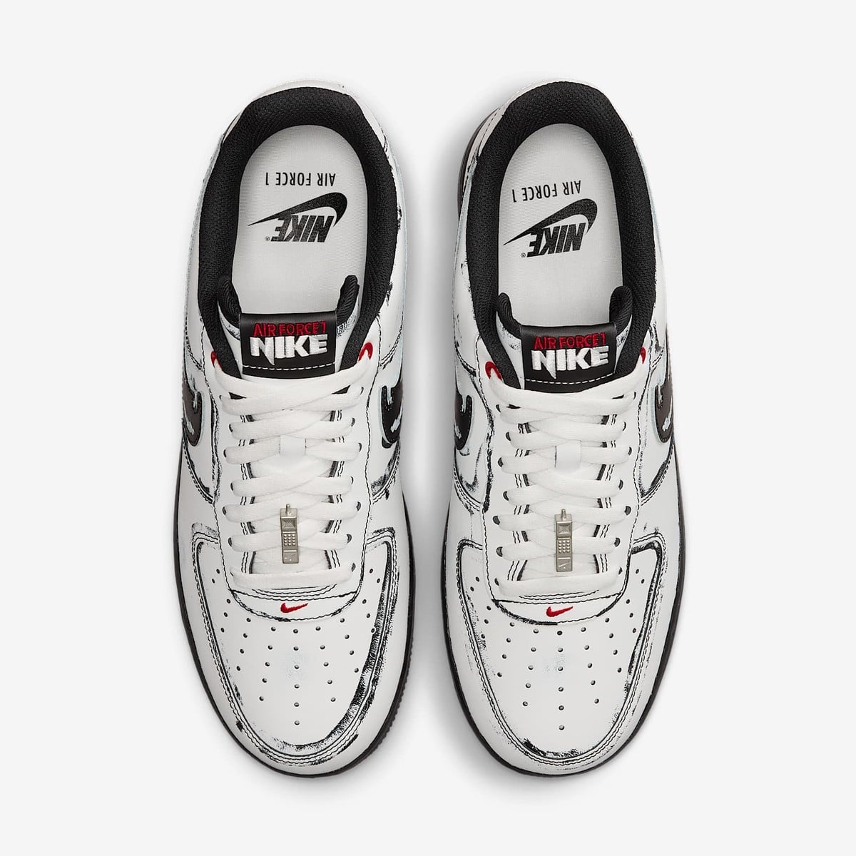 Top view of the white Air Force 1 pair showing the sketched black outlines, tongue tags, and phone lace charms