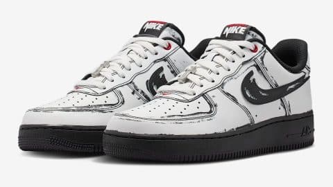 A pair of white Nike Air Force 1 sneakers with black sketched outlines, slashed black Swooshes, and black soles