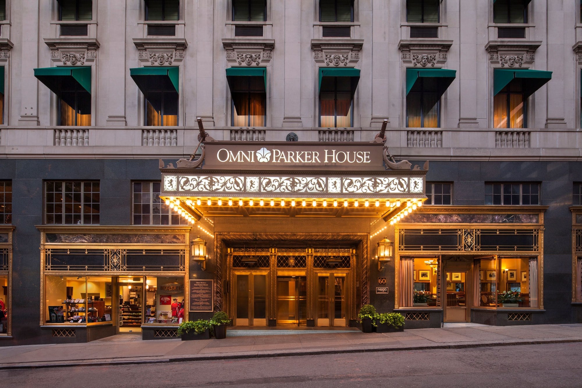 The lit marquee and brass doors of the Omni Parker House entrance in Boston at dusk