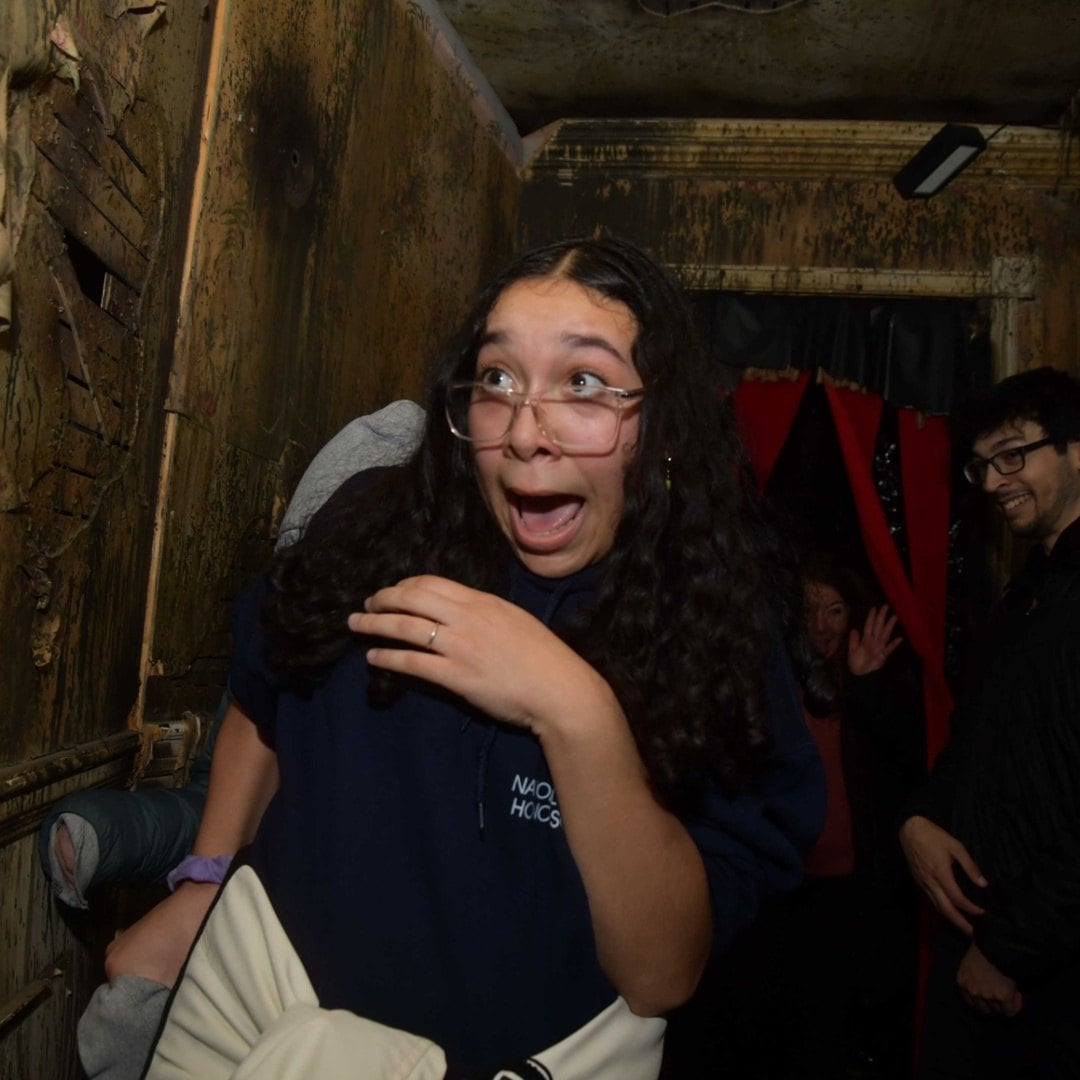 Guests react to a scare in a dark corridor at Pure Terror Scream Park
