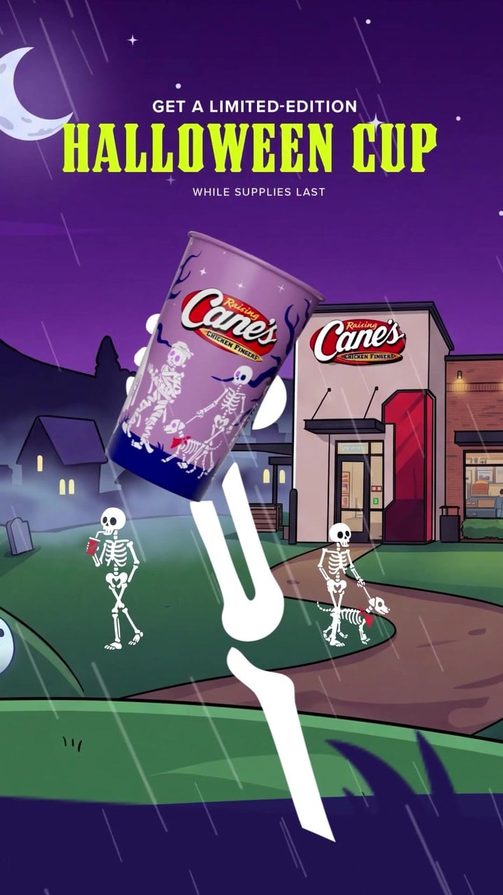 A cartoon skeleton hand holds up a purple Raising Cane's cup outside a Raising Cane's restaurant at night, under the words Get a Limited-Edition Halloween Cup, While Supplies Last
