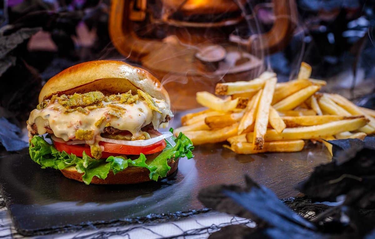 A cheeseburger topped with jalapeños on a brioche bun, served with French fries