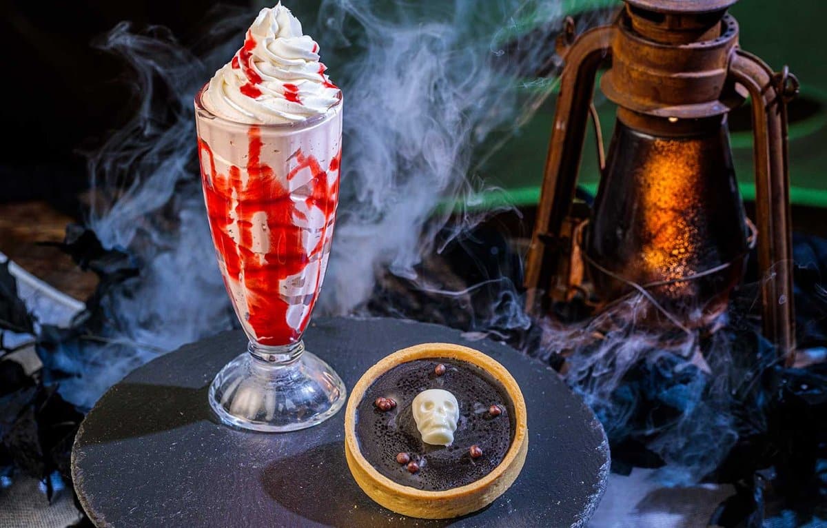 A red-swirled shake beside a dark chocolate tart with a white chocolate skull