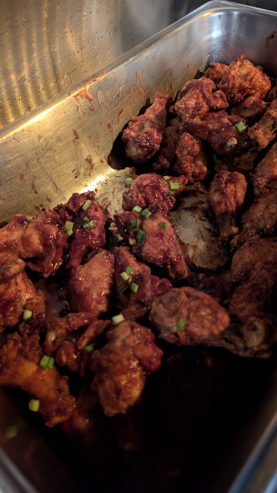 A tray of Black Widow Wings glazed in chipotle blackberry sauce and topped with green onions