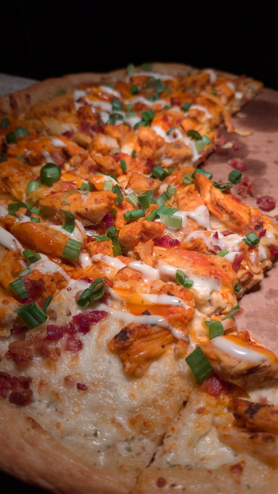 Close-up of the Boo-falo Chicken Pizza with ranch drizzle, buffalo chicken, bacon, and green onions