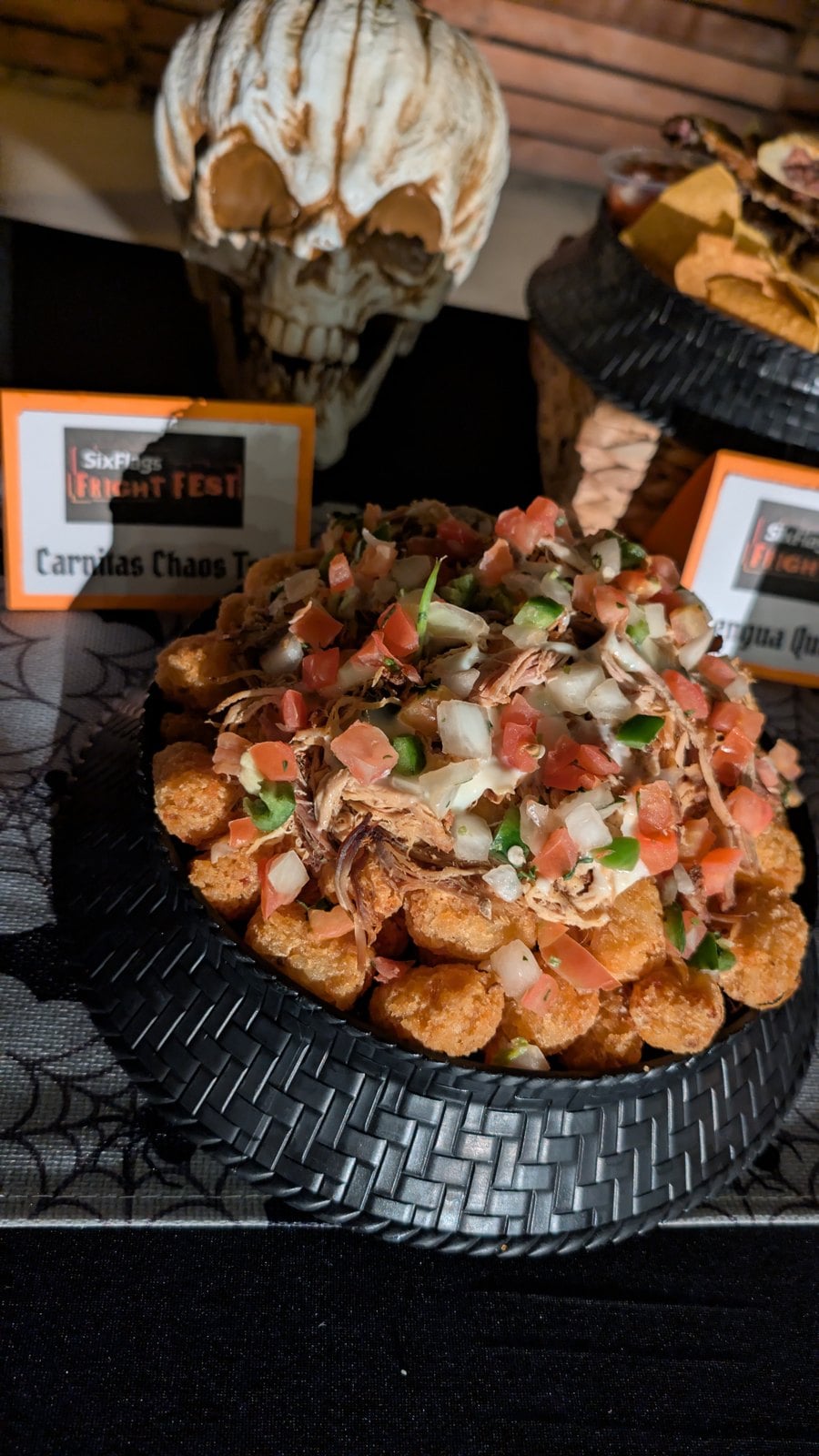 Carnitas Chaos Tots topped with white queso, carnitas, and pico de gallo