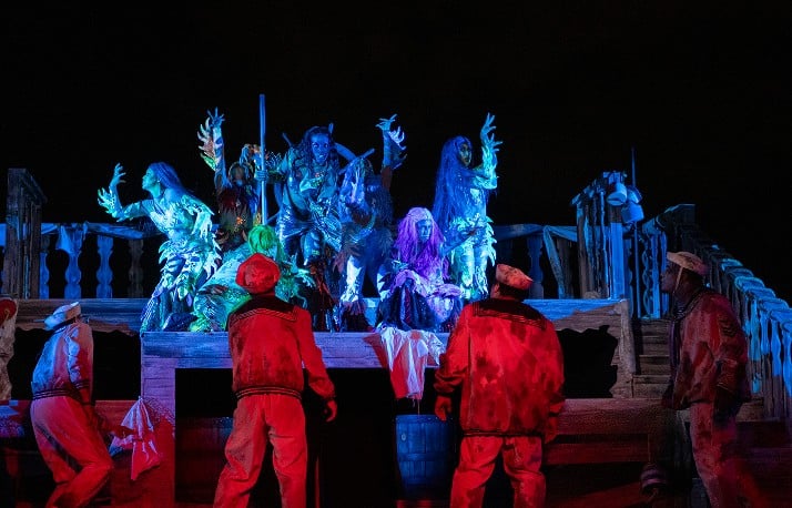 Sirens lit in blue lure red-lit sailors at the Water's Edge scare zone during Howl-O-Scream
