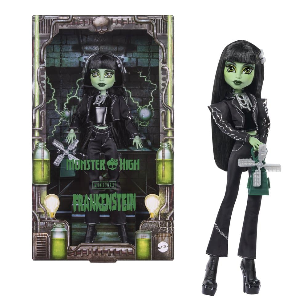 A green-skinned doll with long black hair in a black cropped jacket and trousers, beside its boxed packaging