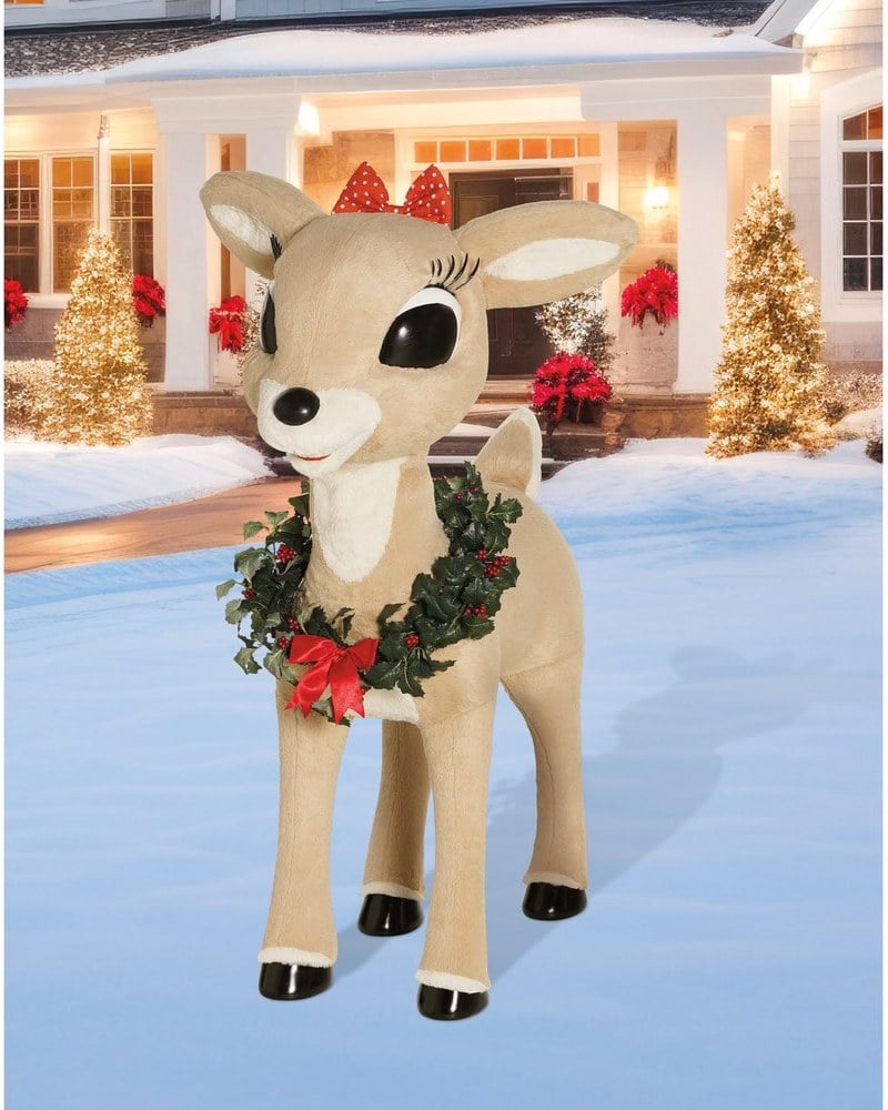 A Clarice reindeer animatronic with a polka-dot bow and a wreath necklace on a snowy lawn
