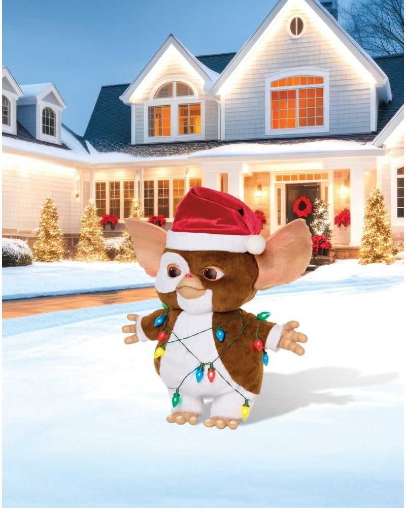 A Gizmo prop from Gremlins in a Santa hat, wrapped in colored lights