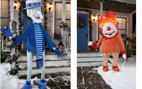 A Snow Miser animatronic in a blue suit beside a Heat Miser animatronic with flaming orange hair, both on snowy front lawns