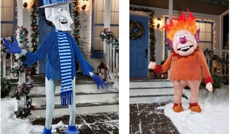 A Snow Miser animatronic in a blue suit beside a Heat Miser animatronic with flaming orange hair, both on snowy front lawns