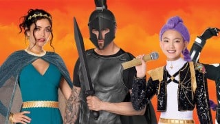 A woman in a teal Greek goddess dress, a man in a black Greek helmet and armor with a sword, and a girl in a purple braided wig and black sequin jacket holding a gold microphone