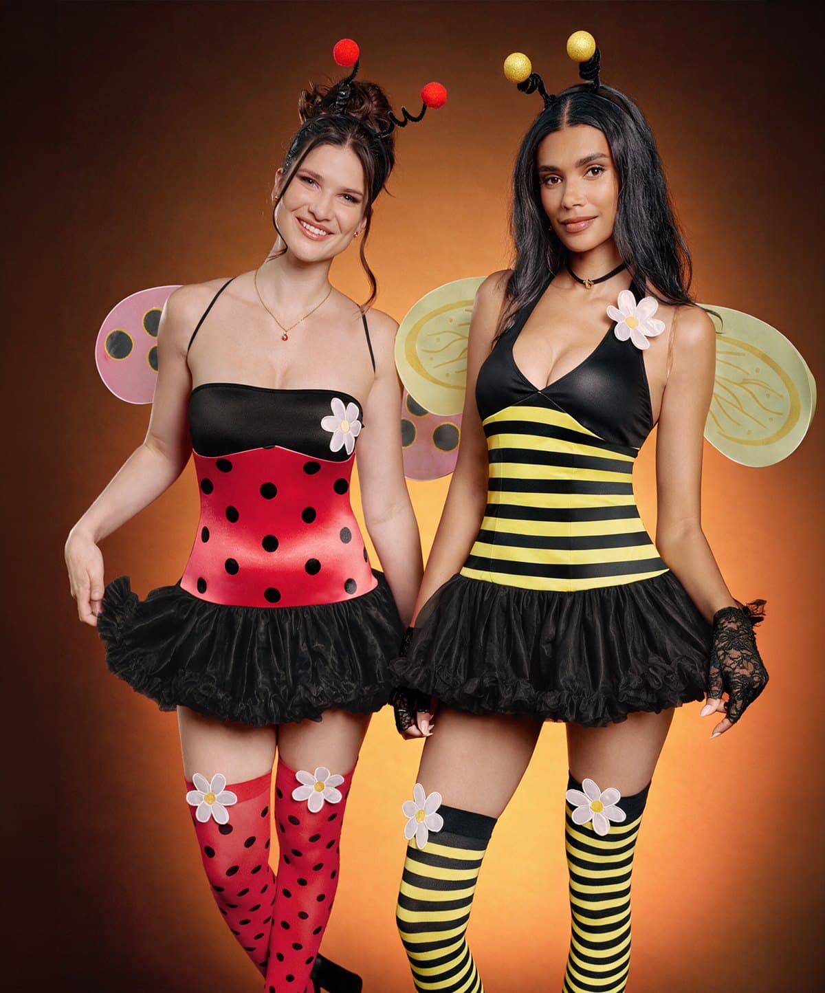 Two women in ladybug and bee costumes with wings and antenna headbands