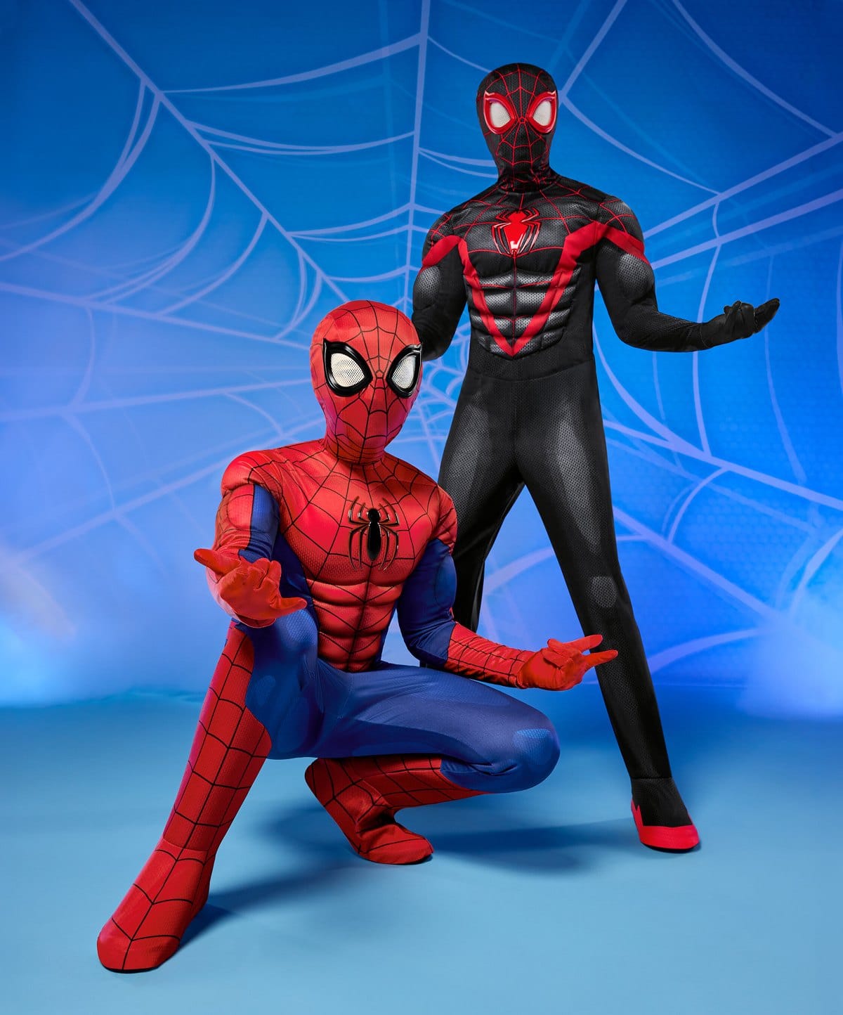 A red and blue Spider-Man costume crouching in front of a black and red Miles Morales costume