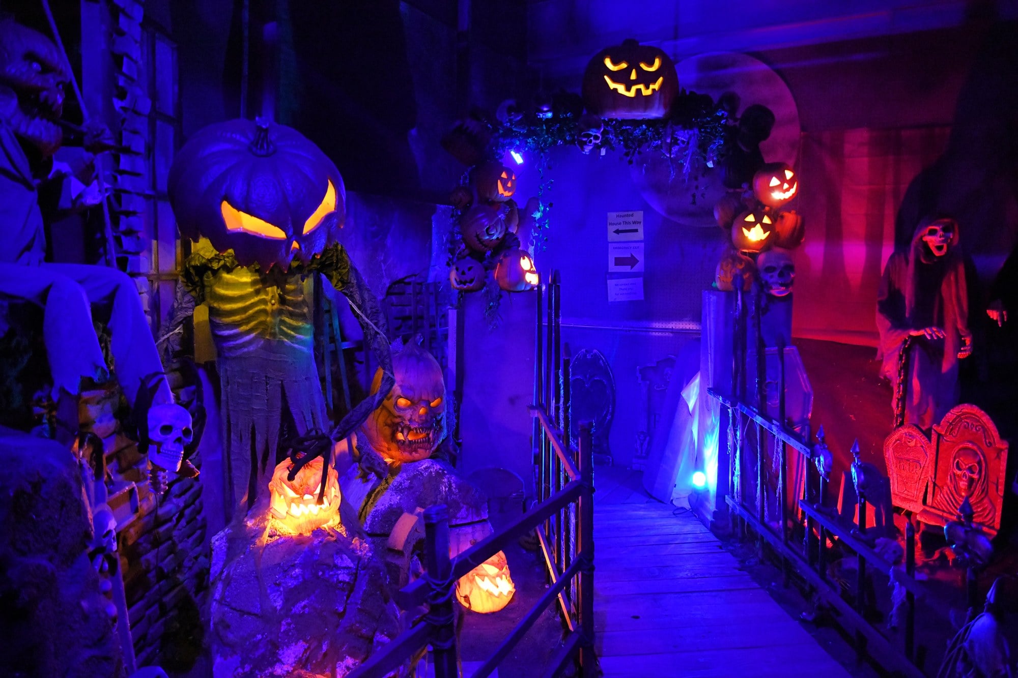 Glowing jack-o'-lanterns, skeletons, and tombstones under purple light inside the Spirit of Halloweentown haunted house