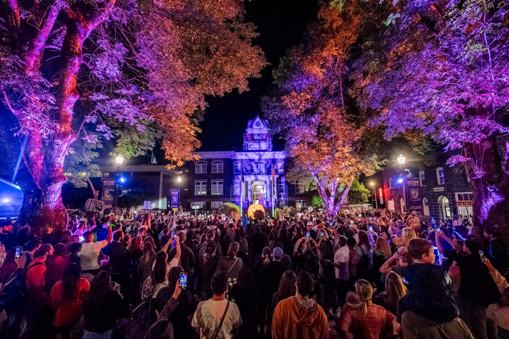A nighttime crowd fills the plaza in front of the lit courthouse in St. Helens during Spirit of Halloweentown