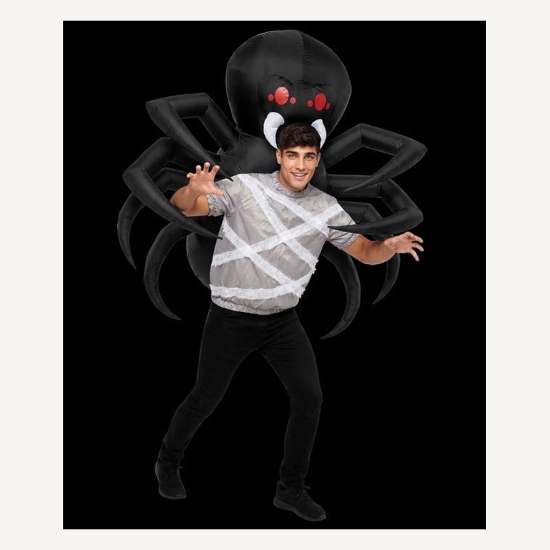 A man wrapped in white web straps with a giant black inflatable spider on his back, its legs spread around him