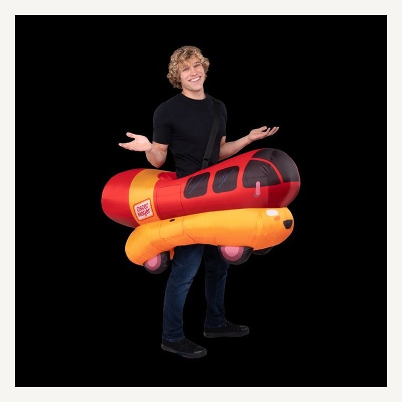 A smiling man wearing an inflatable Oscar Mayer Wienermobile around his waist