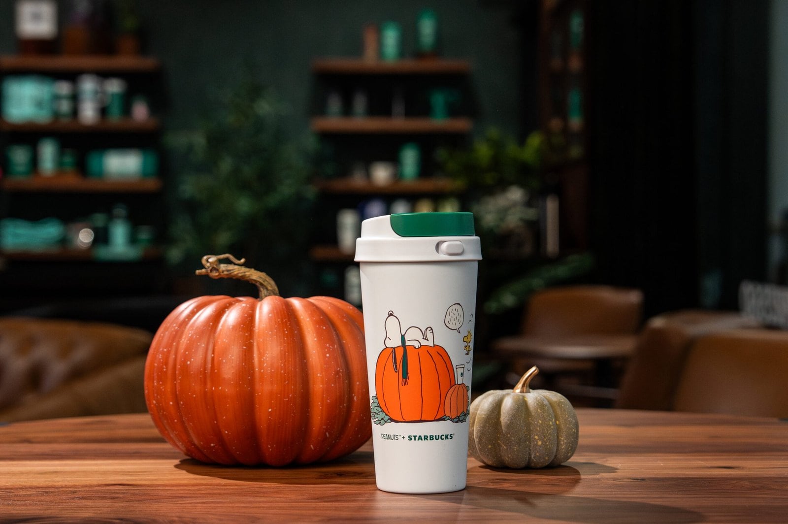 Starbucks and Peanuts Great Pumpkin Tumbler with Snoopy and Woodstock artwork beside a pumpkin