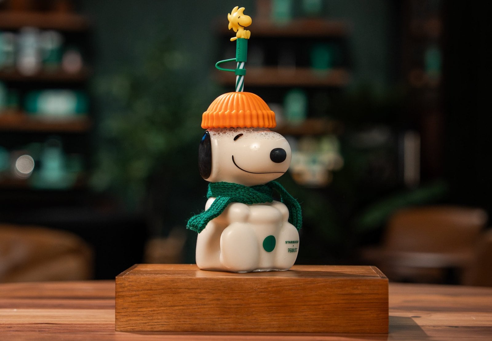 Starbucks and Peanuts Snoopy Glass Cold Cup shaped like Snoopy in an orange pumpkin hat and green scarf with a Woodstock straw topper