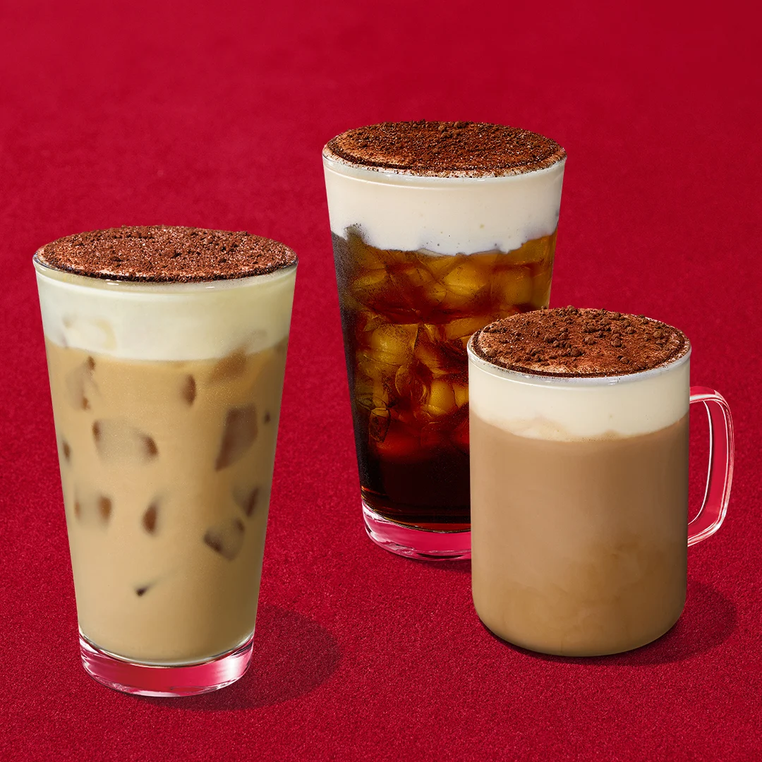 Three Tiramisu Velvet drinks, an iced latte, a cold brew and a hot latte, each topped with cream foam and a cocoa dusting