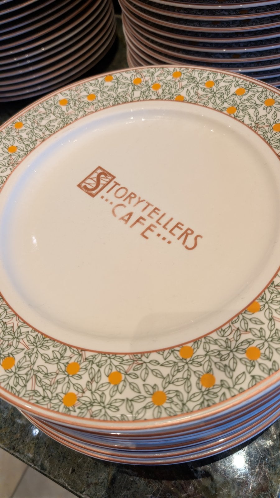 A stack of Storytellers Cafe plates at the buffet
