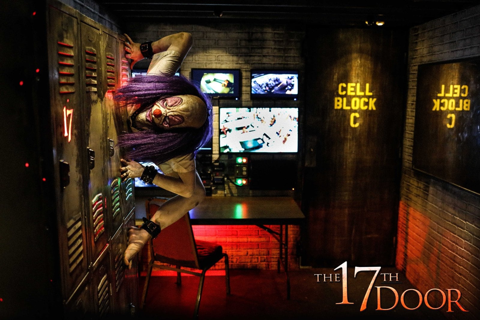 A clown character with purple hair clings sideways to a row of lockers in a room with security monitors and a door marked Cell Block C