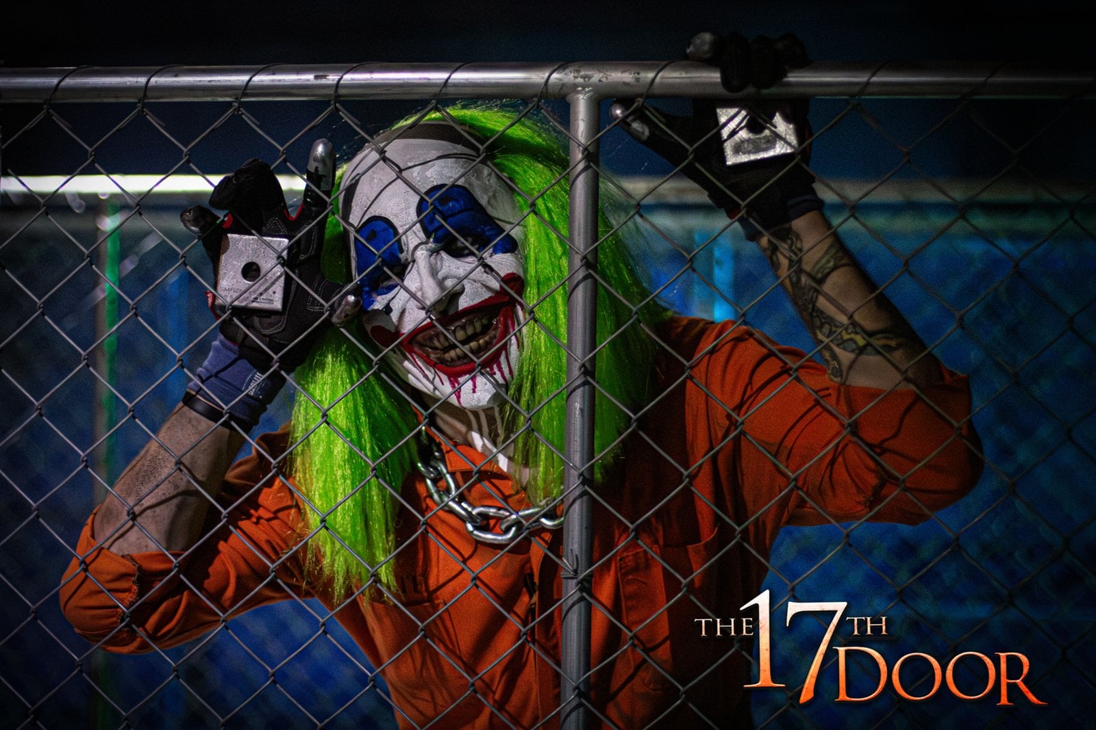 A clown character with green hair and an orange jumpsuit grips a chain-link fence