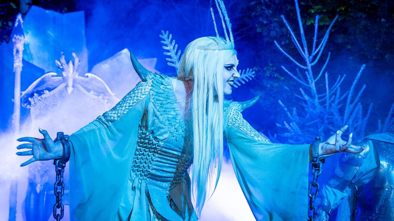Morgana the ice queen in blue light and fog with chained wrists in the Morgana's Frozen Knights scare zone at Toverland