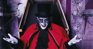 A costumed Ghost Train character in a top hat and red coat rising from a coffin at Tweetsie Railroad