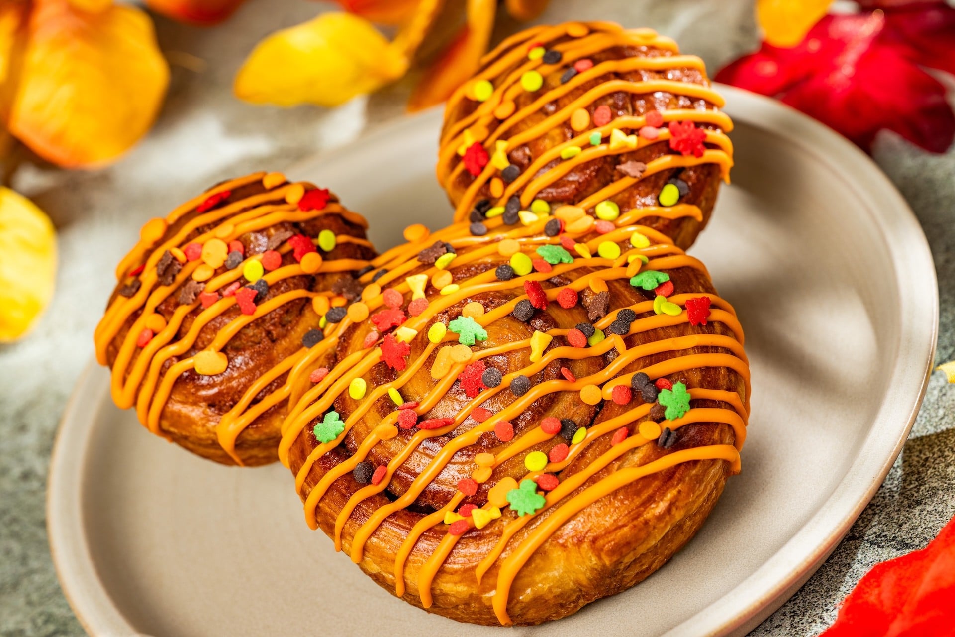 Mickey-shaped cinnamon roll with orange icing and sprinkles